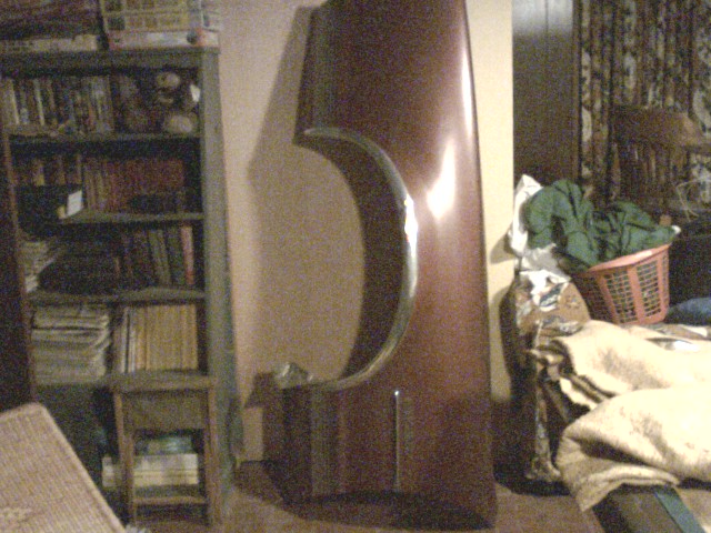 Brown car fender with chrome trim, leaning against a wall indoors