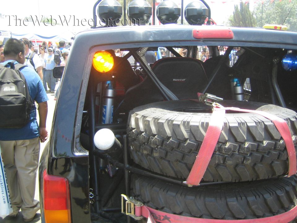 Rear cargo area of an off-road truck with mounted spare tires, light bar and shock reservoirs