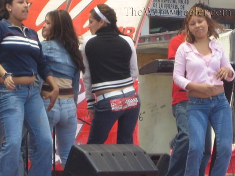 1990 Ford Bronco - Several young people in casual clothes dance on a stage beside a black monitor speaker at an outdoor event.