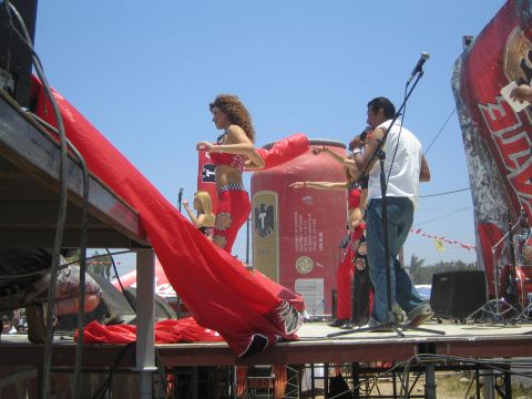 1990 Ford Bronco - Performers on an outdoor stage with a costumed dancer and a singer at a microphone beside a flowing red fabric drape.