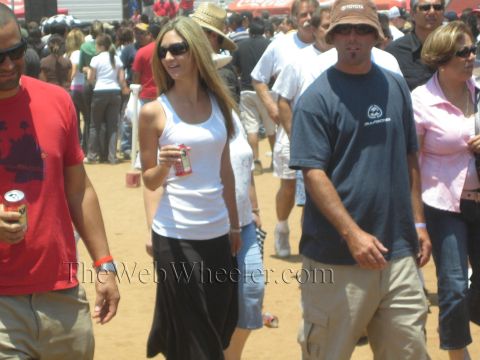 1990 Ford Bronco - crowd of spectators in casual summer clothes and sunglasses walks across a dusty fairground at an outdoor event.