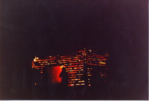 1989 Ford Bronco - A wooden structure engulfed in flames at night, casting an orange glow.
