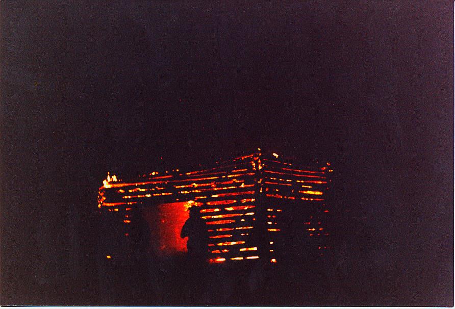 Burning wooden structure at night with orange glow