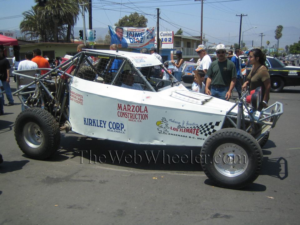 Side view of white tube-frame off-road race buggy with sponsor lettering