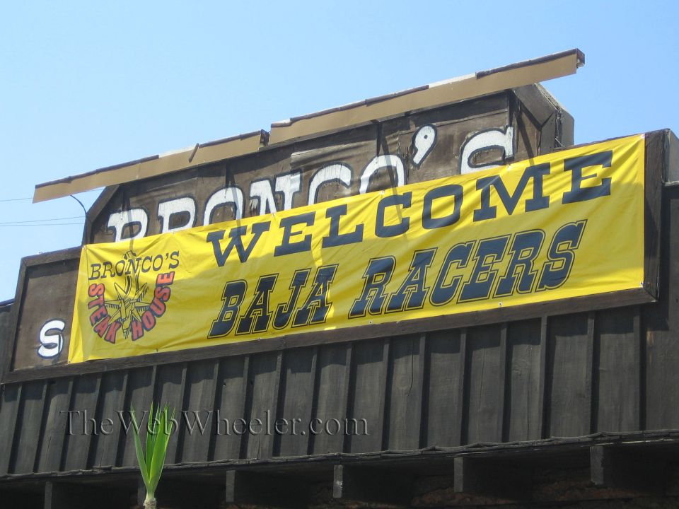 Yellow banner reading Welcome Baja Racers under a Bronco's Steak House sign