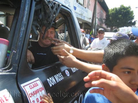 1990 Ford Bronco - driver in a race truck cab labeled Don Moss greets fans reaching in, with a Class Champion sticker on the door.