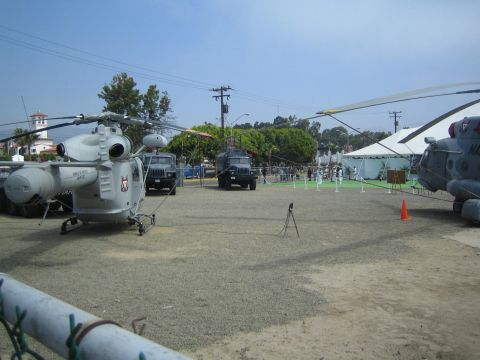 1990 Ford Bronco - Several gray military helicopters and ground vehicles are arranged on a gravel display lot with white tents in the background.