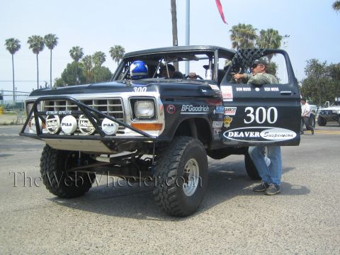 1990 Ford Bronco - Black classic Ford Bronco race truck 300 with Deaver Suspension and BFGoodrich decals, a man standing at the open door.