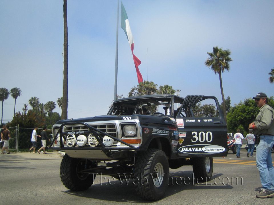 Black Ford Bronco race truck 300 on a street with a Mexican flag and a man walking by