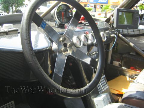 1990 Ford Bronco - Cockpit of an off-road race car with a black steering wheel, center gauges and a dash-mounted Lowrance GPS screen.