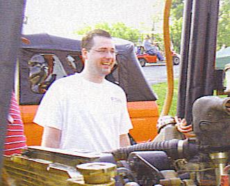 1989 Ford Bronco - Man in white t-shirt next to an orange vehicle, with another vehicle in the background.
