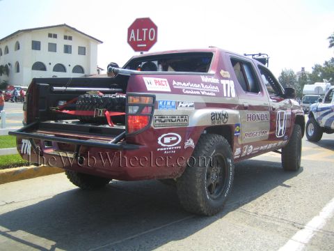 1990 Ford Bronco - Rear three-quarter view of a maroon Honda Ridgeline race truck numbered 178 with bed-mounted gear, parked by an ALTO stop sign.