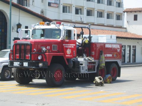 1990 Ford Bronco - red International fire truck numbered 41 and lettered 'Unidad Forestal' parks at a curb with a firefighter and gear nearby.
