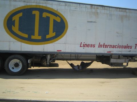 1990 Ford Bronco - white semi trailer with a big yellow 'LIT' logo and 'Lineas Internacionales' text, with someone resting in a hammock below.