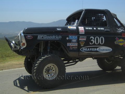 1990 Ford Bronco - Close view of a lifted black number 300 off-road race truck showing BFGoodrich, Deaver Suspension and Sunoco decals over big knobby tires.