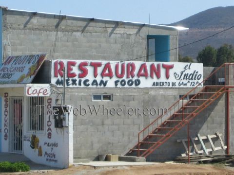 1990 Ford Bronco - cinderblock roadside building with red exterior stairs displays hand-painted signs reading Restaurant el Indio, Mexican Food and Cafe.