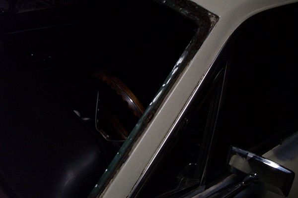 Car interior showing a dark seat, steering wheel, and part of the window frame