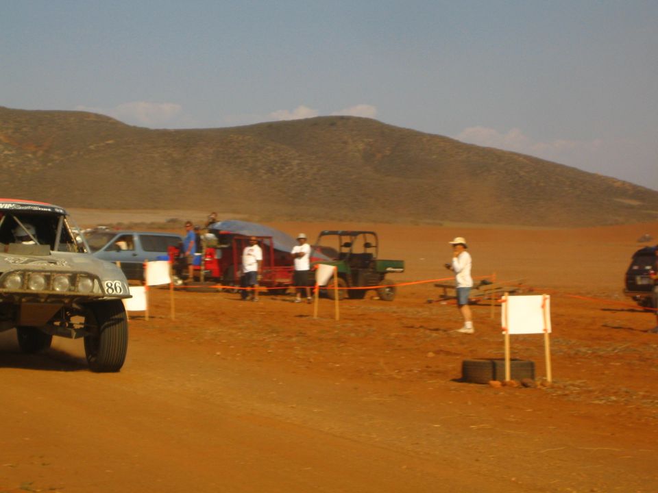Number 86 off-road race truck and spectators at a red dirt desert course