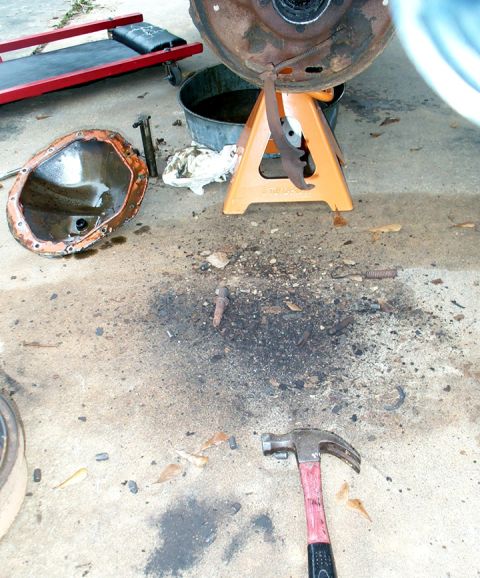 1978 Dodge Power Ram - Differential cover and brake drum removed, with tools and oil pan on the ground, indicating repair work.