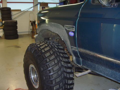 1996 Ford Bronco - A dark teal Ford Bronco is shown with large, aggressive off-road tires and a blue FSB sticker on the fender.