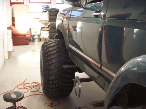 1996 Ford Bronco - A green 1996 Ford Bronco is shown from the side, large off-road tires and chrome trim in a garage setting.