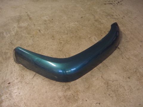 1996 Ford Bronco - Green bumper corner piece, likely from a vehicle, lying on a concrete surface.