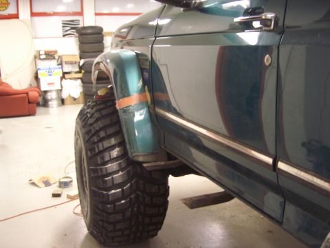 1996 Ford Bronco - Side view of a 1996 Ford Bronco, showing its green fender and door with chrome trim.