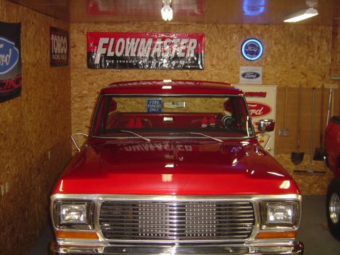 1978 Ford Bronco - Front view of a red 1978 Ford Bronco parked inside a garage with Ford memorabilia on the wall.