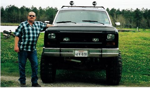 1981 Ford Bronco - A man poses next to a black SUV with a license plate from Texas.