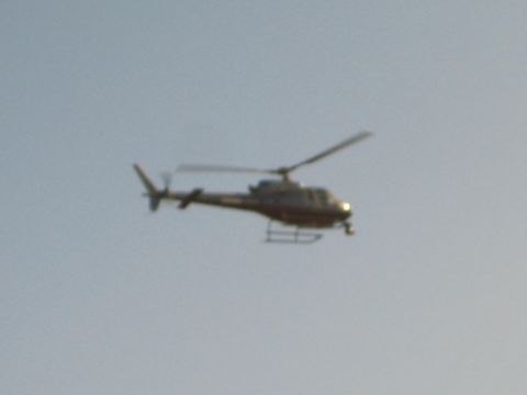 1990 Ford Bronco - small light-colored helicopter flies against a pale blue sky.