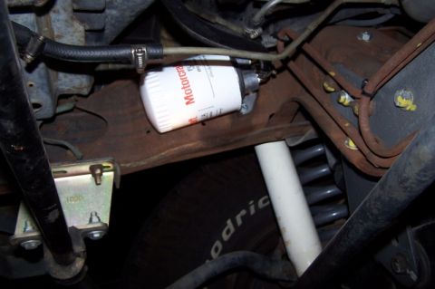 1990 Ford Bronco - Close-up of a transmission filter and suspension components under a vehicle.