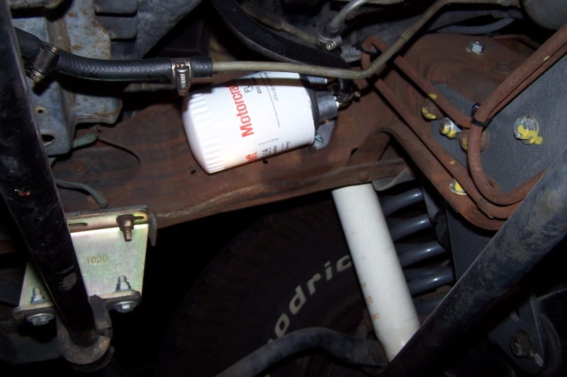 Motorcraft transmission filter attached to rusty frame with hoses and suspension parts visible