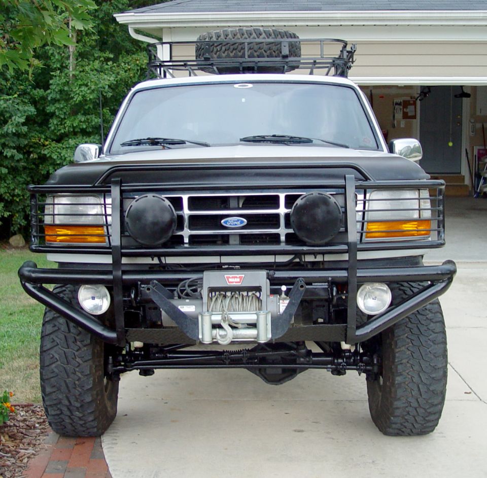 Lifted white 90s Ford Bronco front view with Warn winch bumper, grille guard and roof rack