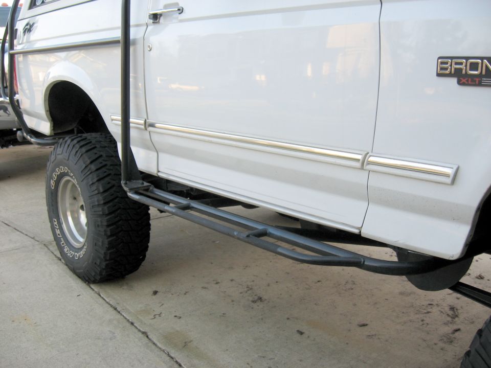 White Ford Bronco XLT side view with steel tube rock sliders and Goodyear mud tires
