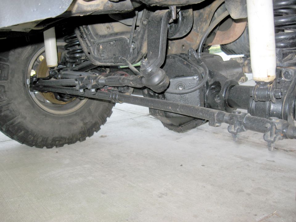 Underside view of a lifted 4x4 solid front axle, differential, tie rod and shock