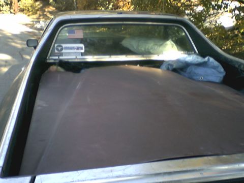 1973 Ford Ranchero - The bed of a pickup truck is covered, with stickers on the rear window.