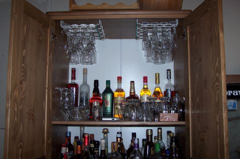 1990 Ford Bronco - A liquor cabinet stocked with various bottles of spirits and wine glasses hanging above.
