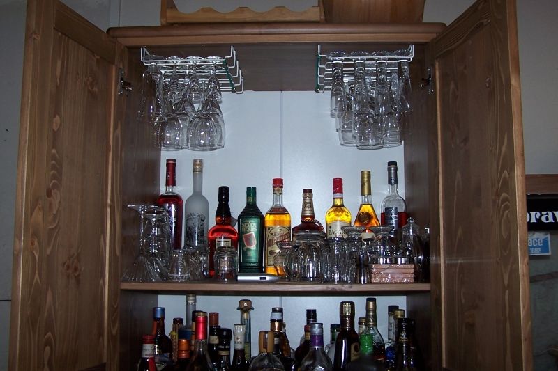 liquor cabinet filled with bottles of alcohol and hanging glassware