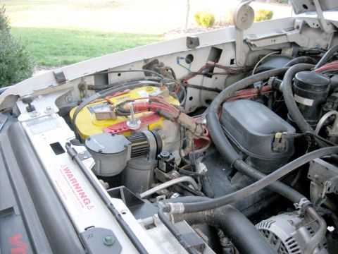 1996 Ford Bronco - Close-up view of the engine bay, highlighting the battery and associated components.