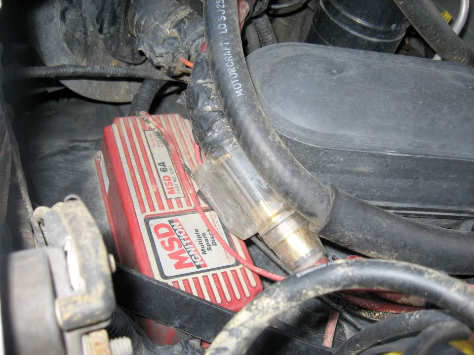 Red MSD ignition box with white lettering and silver accents, surrounded by black hoses and wiring