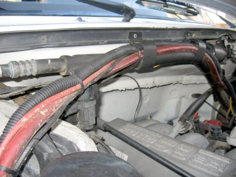 1996 Ford Bronco - Close-up view of the engine bay wiring harness, showing red and black cables secured by black zip ties.