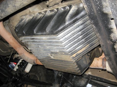 1996 Ford Bronco - Close-up of a ribbed transmission oil pan, showing part of the exhaust and suspension system.