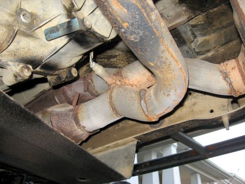 1996 Ford Bronco - Underside view of a vehicle's exhaust system, revealing rust and a damaged oxygen sensor.