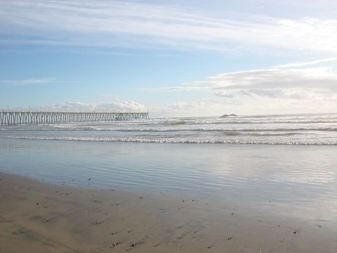 1984 Ford Bronco - A wide view of the ocean and a pier on a partly cloudy day.
