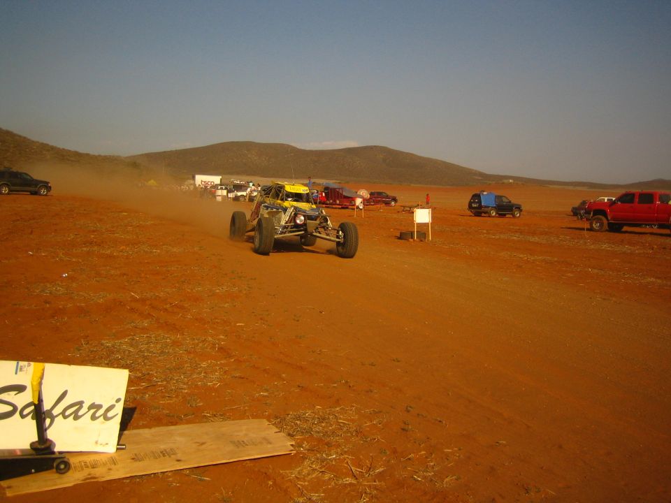 Yellow off-road buggy on desert course behind Safari sign