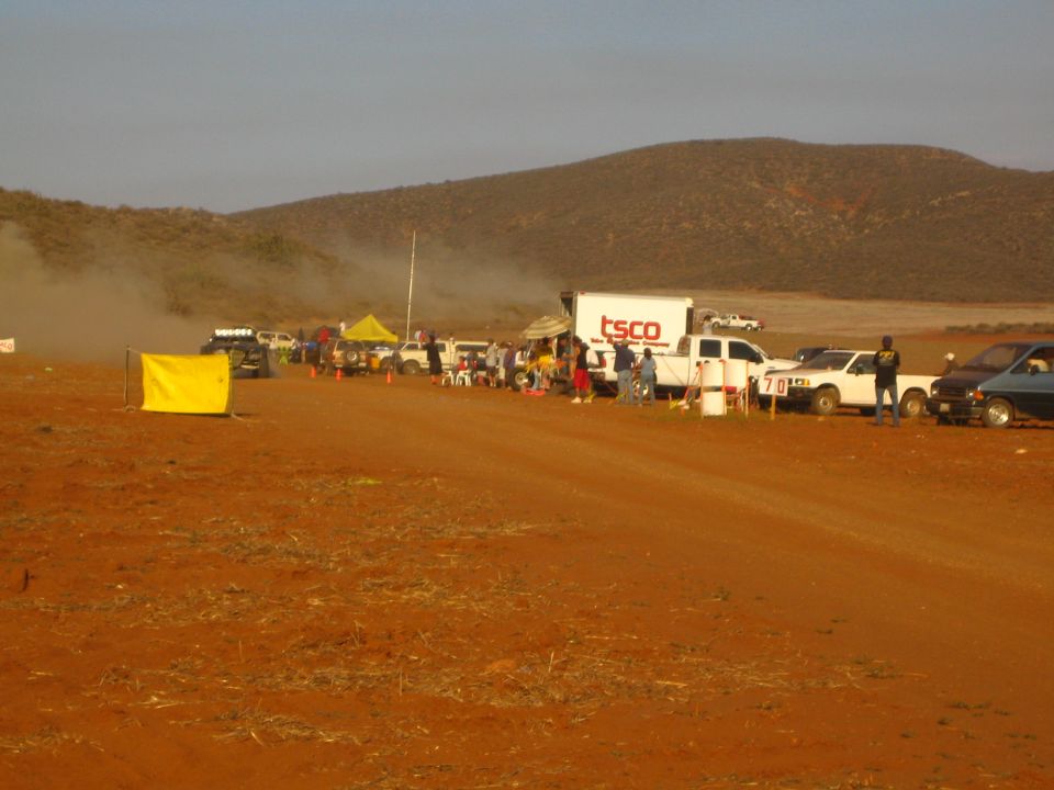 Desert race pit line with TSCO truck, pickups and yellow flag