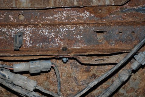 1996 Ford Bronco - Close-up view of corroded vehicle frame components and electrical connections.