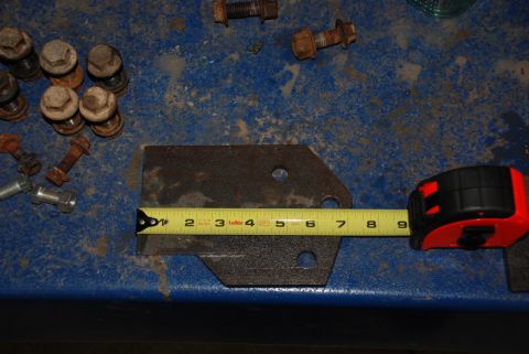 1996 Ford Bronco - Metal bracket and assorted bolts on a blue surface, measured with a tape measure.