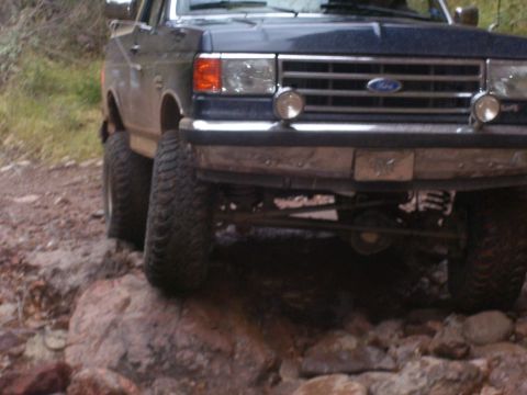 1991 Ford Bronco - Ford F-Series truck with lifted suspension and large off-road tires navigating rocky terrain.