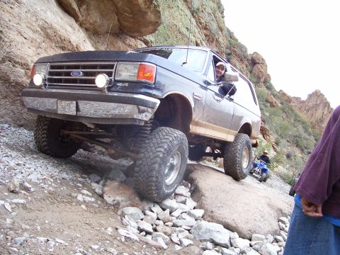 1991 Ford Bronco - Ford Bronco navigating a difficult rocky off-road path with an ATV visible behind it.